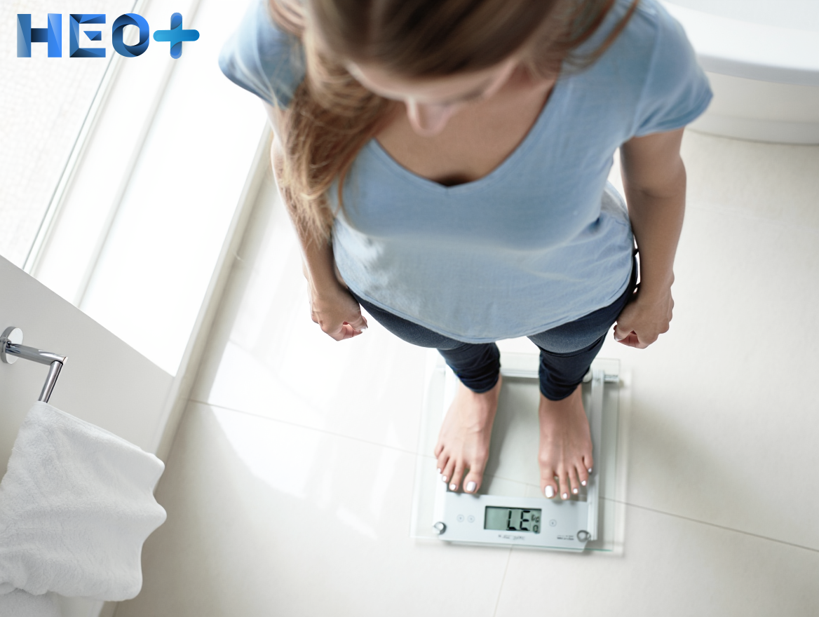 Девушка взвешивается и смотрит на весы